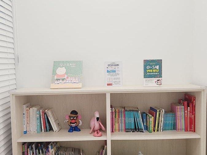 그림책이 가득한 책장과 캐릭터 벽 장식이 있는 기다림 마루